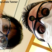 Zahnarzt mit Mundschutz und Lupenbrille sowie Assistentin mit Mundschutz und Schutzbrille aus Patientensicht