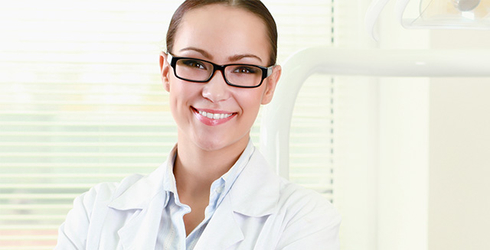 Eine junge Ärztin im Kittel mit Brille lächelt