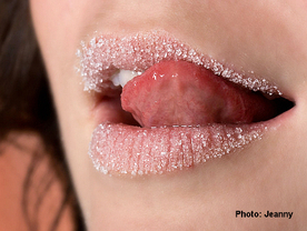 Zunge streicht über Zuckerkristalle auf Lippen